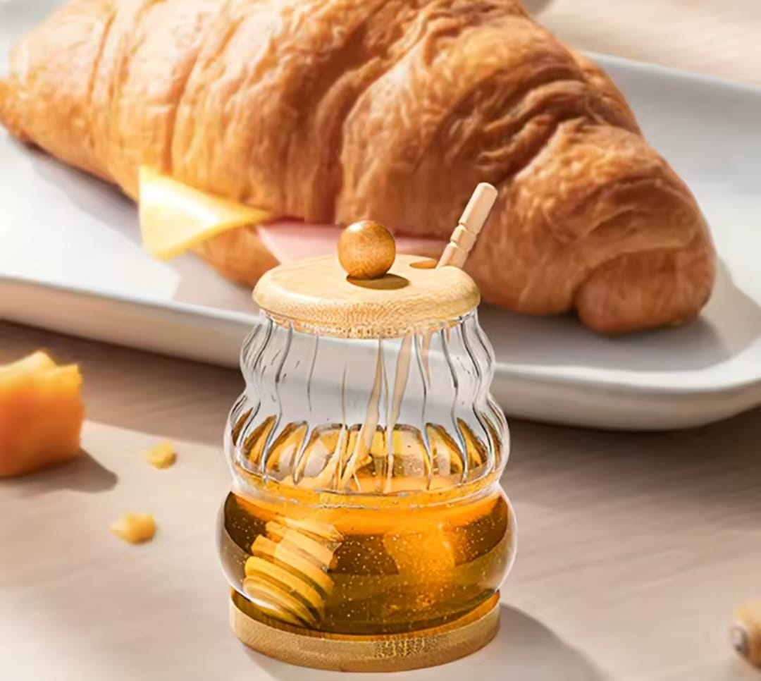 Glass honey storage jar with wooden lid and stirring stick